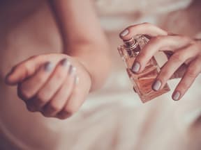 Eine Frau sprüht Parfum auf ihr Handgelenk
