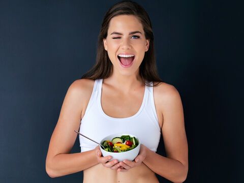 schlanke Frau hält veganen Salat vor sich