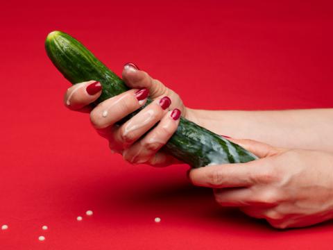 Frau hält Gurke als Sexspielzeug in der Hand