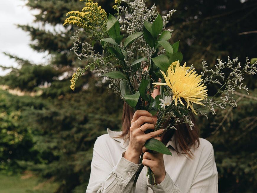 Frau mit Blumen vor Gesicht 