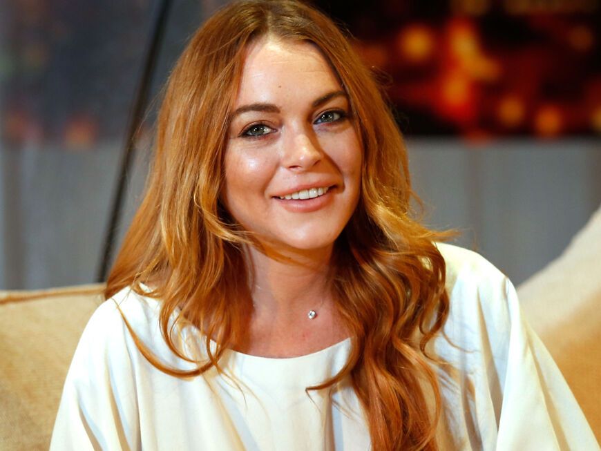 Lindsay Lohan sitzt lächelnd auf Sofa