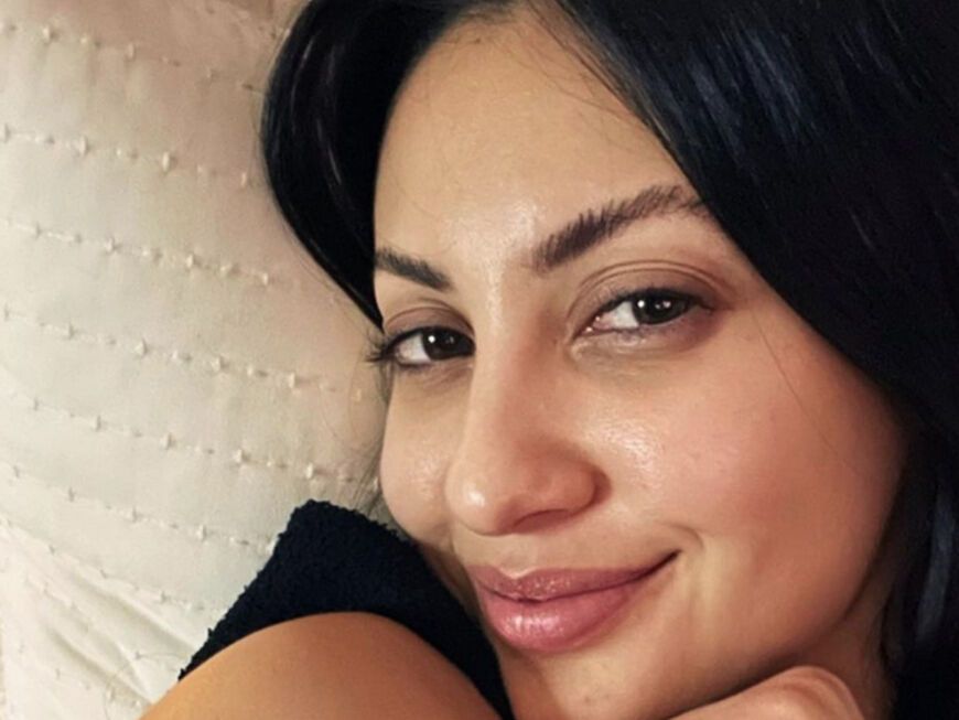 Francia Raisa lächelt ungeschminkt im Bett auf Instagram-Selfie
