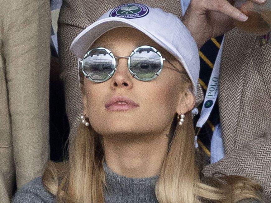 Ariana Grande guckt konzentriert mit Sonnenbrille und Cap beim Wimbledon 2023