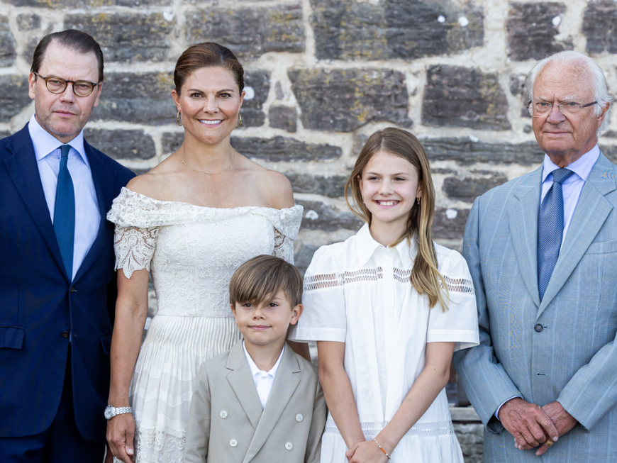 Prinz Daniel, Kronprinzessin Victoria, Prinz Oscar, Prinzessin Estelle und König Carö Gustaf vor einer Mauer
