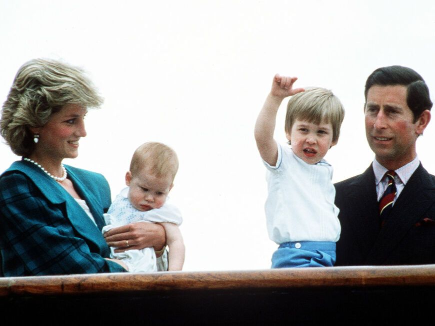 Prinzessin Diana mit Harry und William sowie Prinz Charles stehen lächelnd nebeneinander
