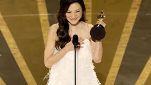 Michelle Yeoh mit Oscar-Trophäe in der Hand grinst vor Mikro auf der Bühne