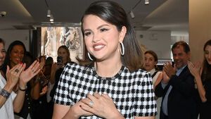 Selena Gomez grinst und fasst sich ans Herz