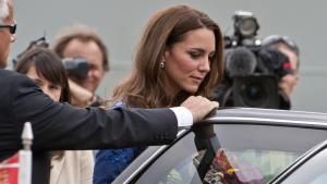 Prinzessin Kate steigt in ein Auto, ein Sicherheitsmann hält ihr die Tür auf. Im Hintergrund haben sich Paparazzi versammelt.