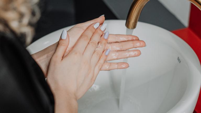 Frau mit lackierten Nägeln wäscht Hände
