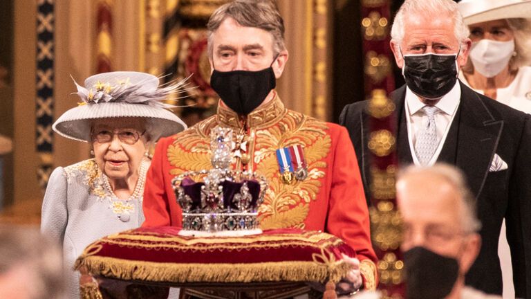 Prinz Charles läuft neben Queen Elizabeth Diener vor ihnen trägt Krone