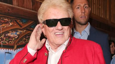 Heino lacht mit Sonnenbrille und fasst sich ans Ohr