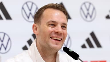 Manuel Neuer lacht in einer Trainingsjacke bei einer Pressekonferenz