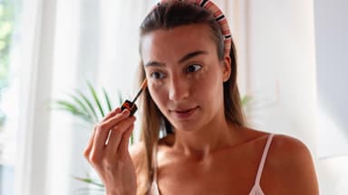 Frau verwendet Concealer vor Spiegel