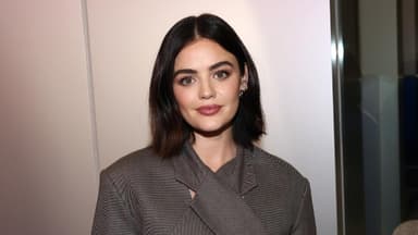 Lucy Hale steht vor einer Wand & guckt in die Kamera