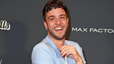 Luca Hänni lacht mit Zähnen im hellen Hosenanzug