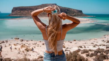 Frau mit langen Haaren blickt aufs Meer