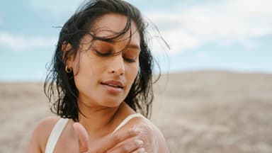 Frau am Strand cremt sich ein