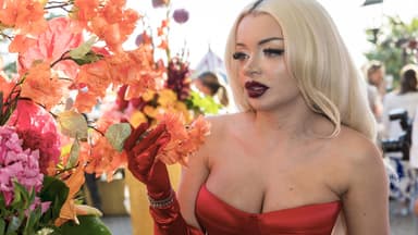 Katja Krasavice guckt ernst zur Seite, neben ihr Blumen