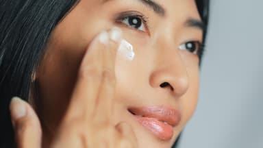 Asiatische Frau mit Augencreme