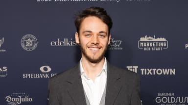 Fabian Hanis posiert im Anzug, strahlt