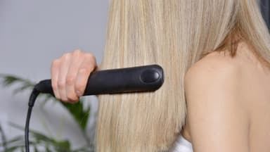 Frau glättet Haare