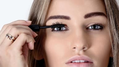 Mascara mit 3-fach Effekt Frau mit langen Wimpern trägt Mascara auf