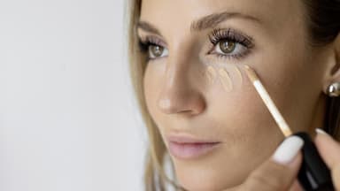 Frau trägt Concealer auf
