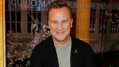 Guido Maria Kretschmer lächelt vor Blumen-Bouquet