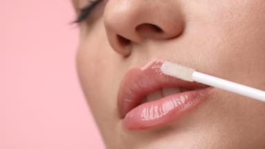 Frau mit vollen Lippen trägt Lipgloss auf