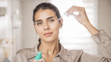 Frau mit dunklen Haaren benutzt Serum