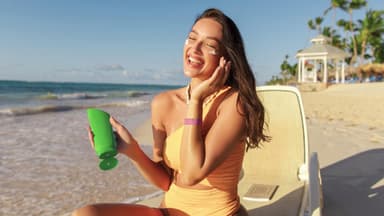 Frau cremt sich am Strand ein