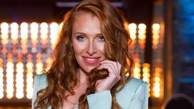 Georgina Fleur lächelt und hält ihre roten Haare fest
