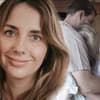Anna Heiser blickt in die Kamera, im Hintergrund heult sie sich in Geralds Armen aus