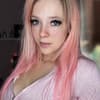 Anne Wünsche mit rosa Haaren, im Hintergrund sieht man sie verschwommen als Grinch verkleidet