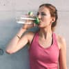 Frau in sportlichen Top trinkt aus einer Flasche