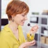 frau isst im büro einen gesunden obstsalat
