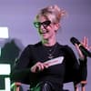 Kelly Osbourne lacht mit Brille und Mikrofon in der Hand