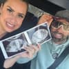 Virginia Weiß und Ehemann Andrew lächeln und zeigen ein Ultraschallbild