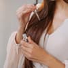 Frau trägt Haaröl auf lange braune Haare auf