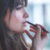 Frau mit dunklen Haaren malt Lippenkontur nach