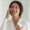Frau trägt lachend Anti-Aging-Creme auf