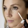 Frau trägt Concealer auf