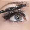 Frau mit blauen Augen benutzt Mascara