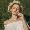 Frau mit Blumenkranz auf grüner Wiese