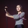 Olivia Rodrigo mit Mikrofon und traurigem Blick