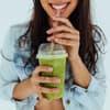 Eine Frau trinkt einen grünen Smoothie