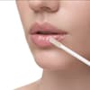 Frau trägt Lippenöl auf