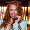 Georgina Fleur lächelt und hält ihre roten Haare fest