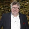 Michael Schanze im Anzug, Busch im Hintergrund