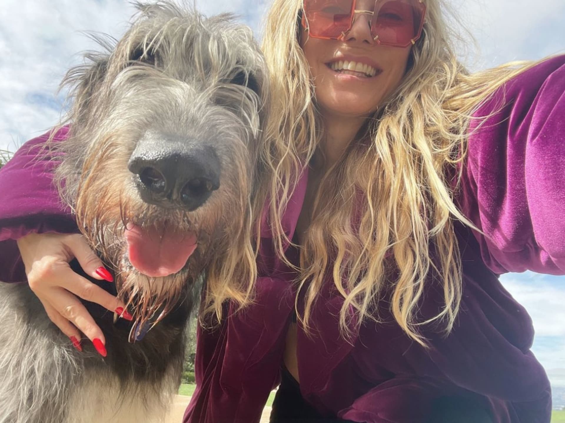 Heidi Klum hat den Arm um Hund Anton gelegt und grinst in die Kamera